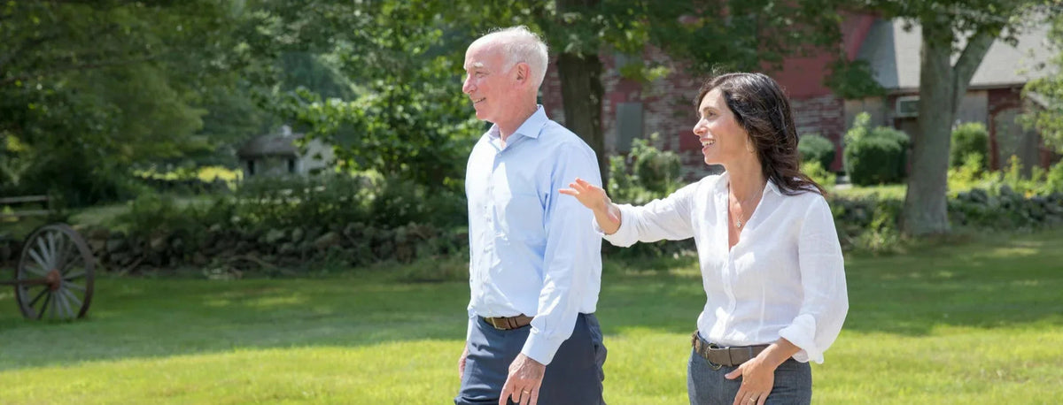Congressman Courtney walks beside a gesturing woman across a sunny lawn at Randalls