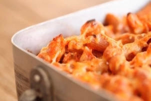 Baked penne al forno pasta casserole with melted golden cheese in a metal baking dish