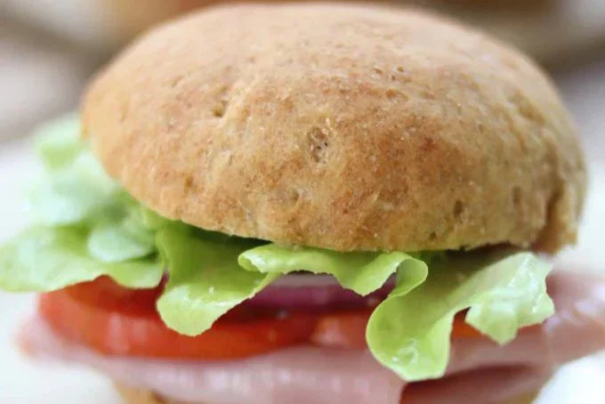 Close-up of hearty flax and Einkorn bread roll sandwich showing whole-grain texture with lettuce and tomato