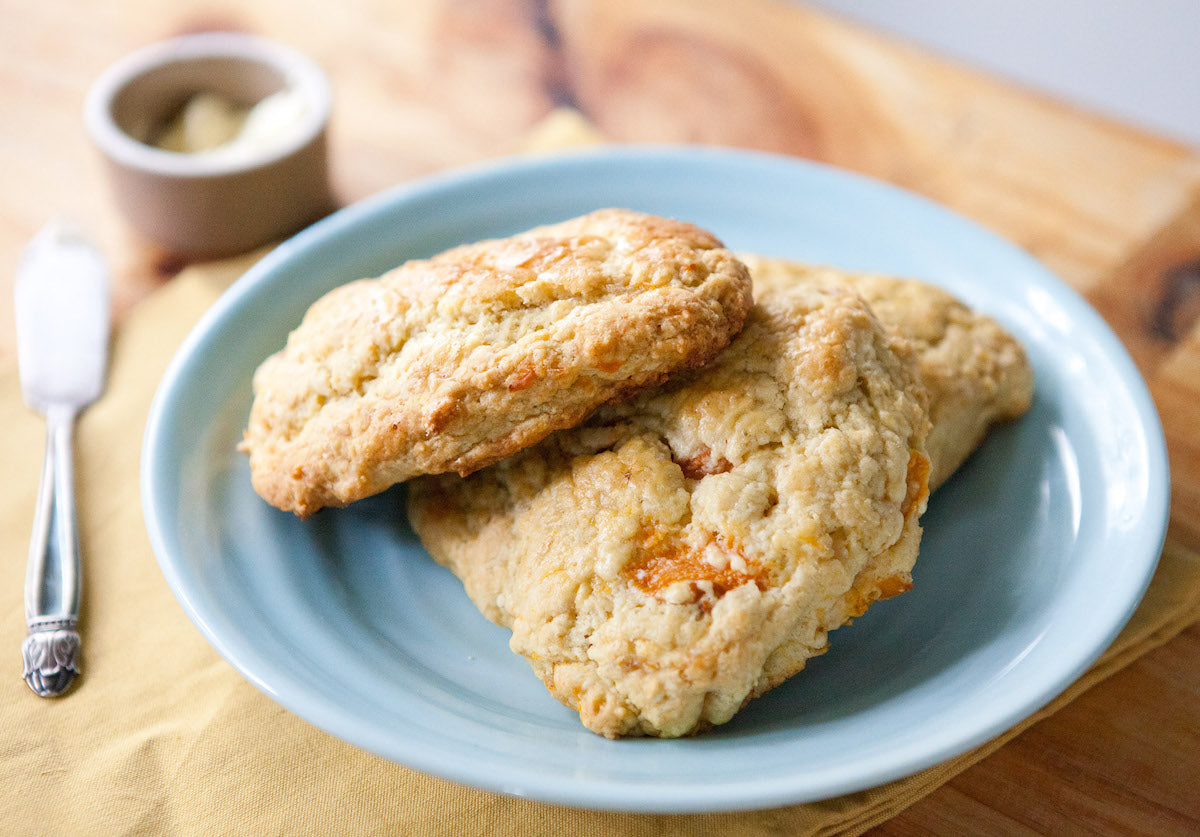 Close-up of two triangular Einkorn scones with golden crumbly texture on a blue plate on a wooden board